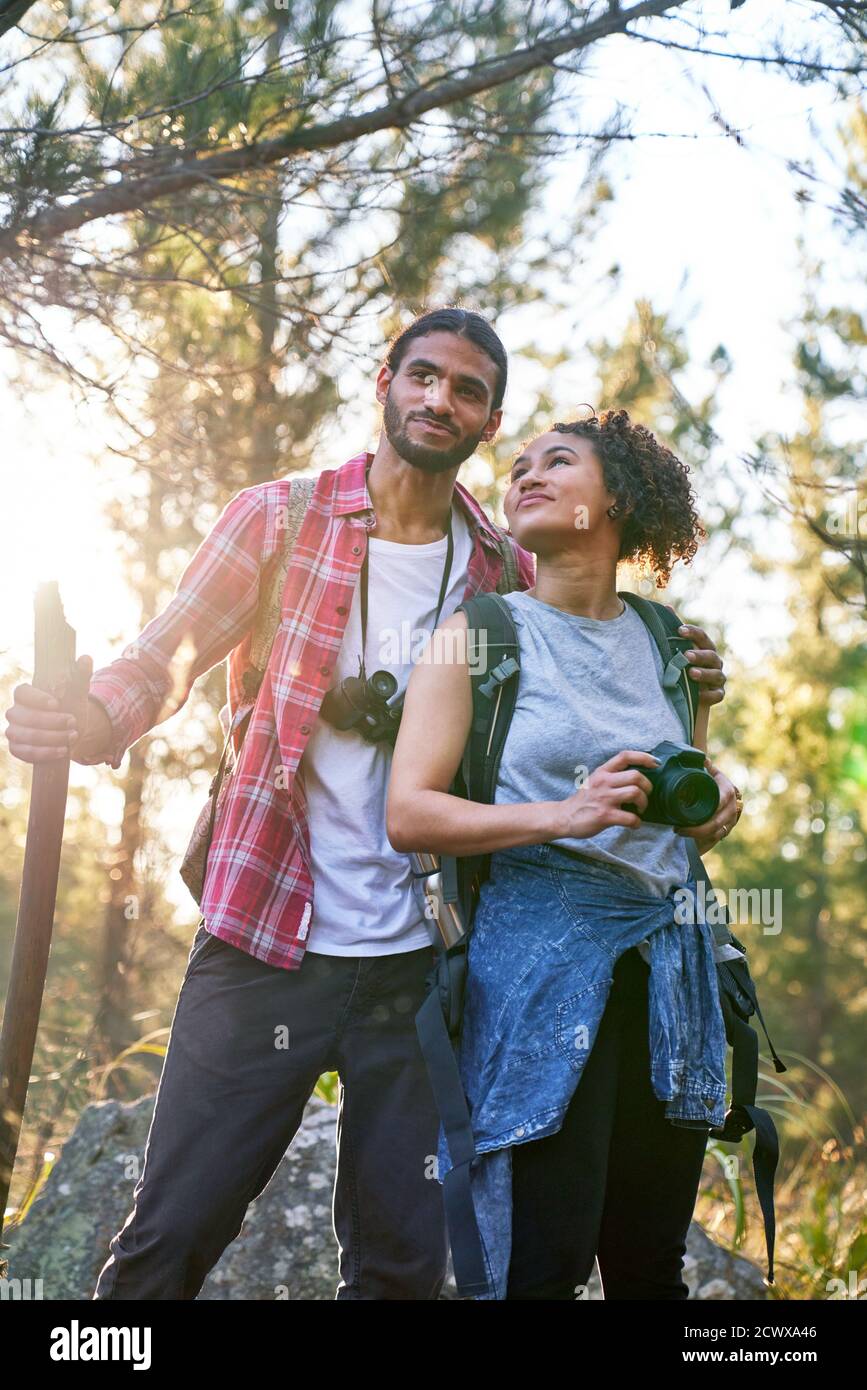 Joyeux jeune couple randonnée avec appareil photo et jumelles dans le soleil bois Banque D'Images
