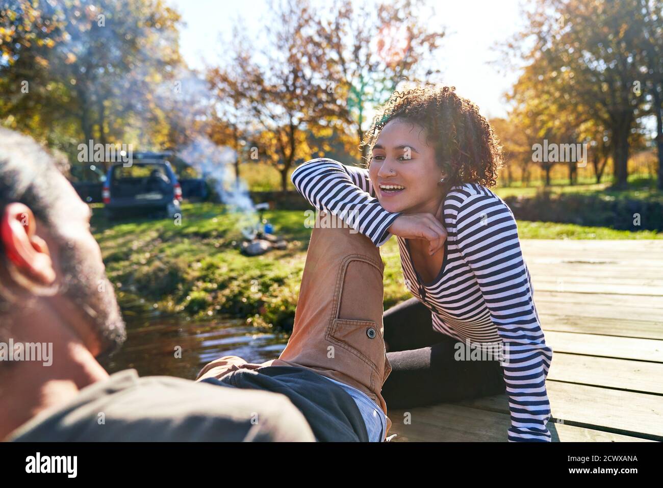 Un jeune couple heureux se détendant sur le quai ensoleillé de l'automne Banque D'Images