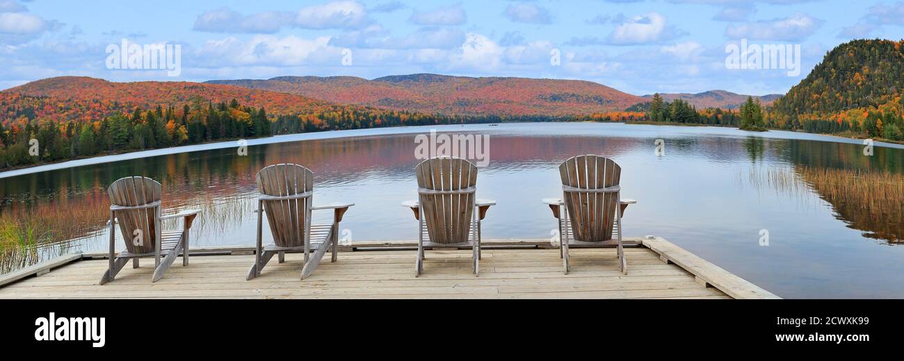 Fauteuils en bois sur la rive du lac Monroe et couleurs automnales dans le parc national du Mont-Tremblant, au Québec Banque D'Images