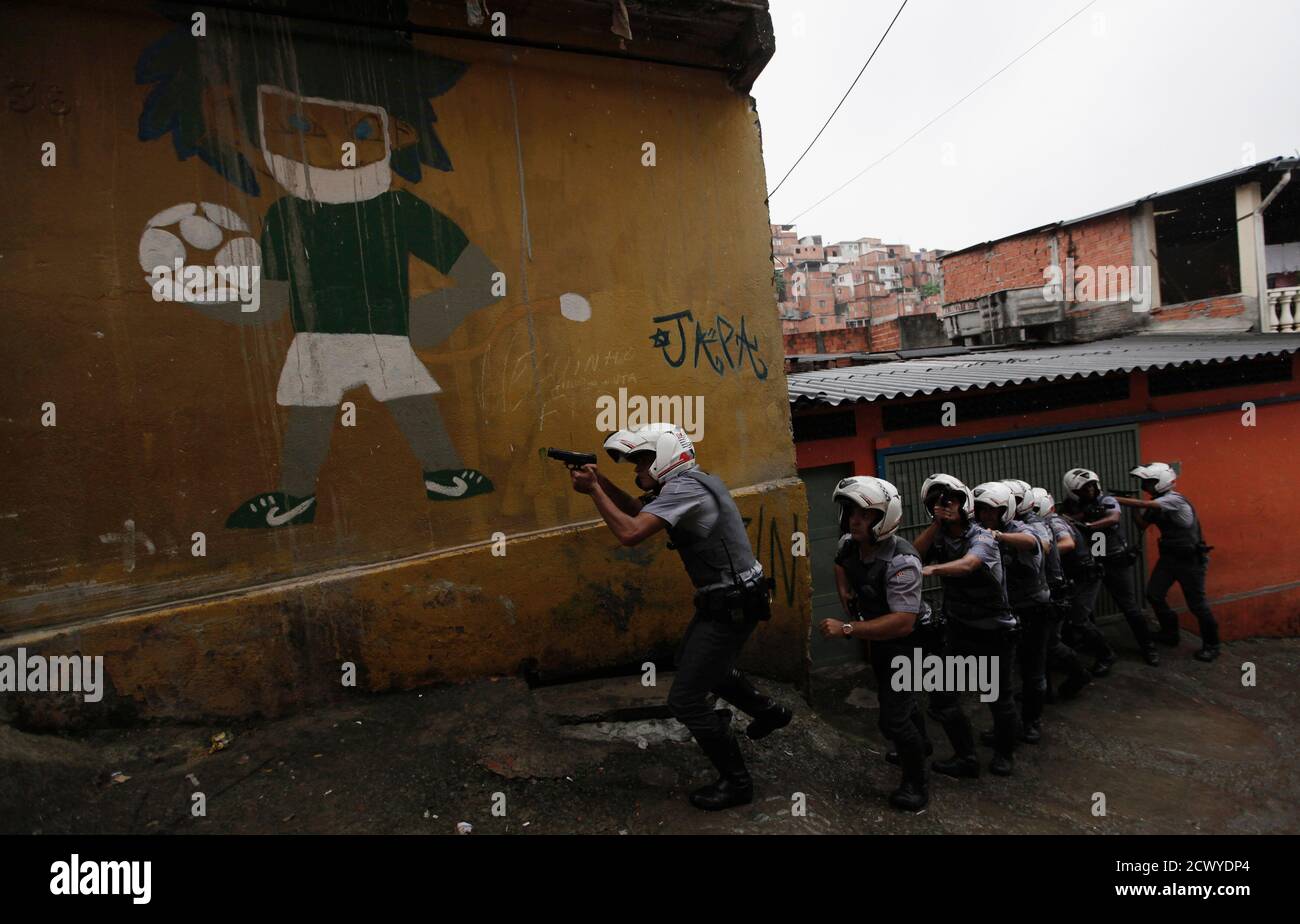 Police officers patrol next to wall graffiti of a soccer player at the  Brasilandia favela during a security operation in Sao Paulo November 9,  2012. Some 90 police murders have occurred this