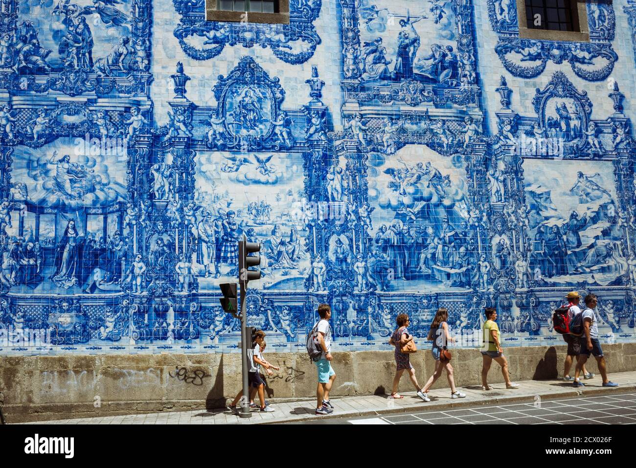 Porto, Portugal : les gens se promeunent devant le mur bleu azulejo d'Eduardo Leite sur les murs de la chapelle Capela das Almas. Banque D'Images