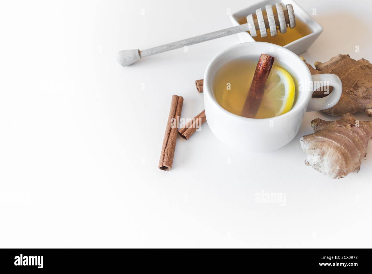 une tasse de perfusion et des ingrédients comme le gingembre, le citron, la cannelle et le miel sur une table blanche. Concept de remède à la maison Banque D'Images