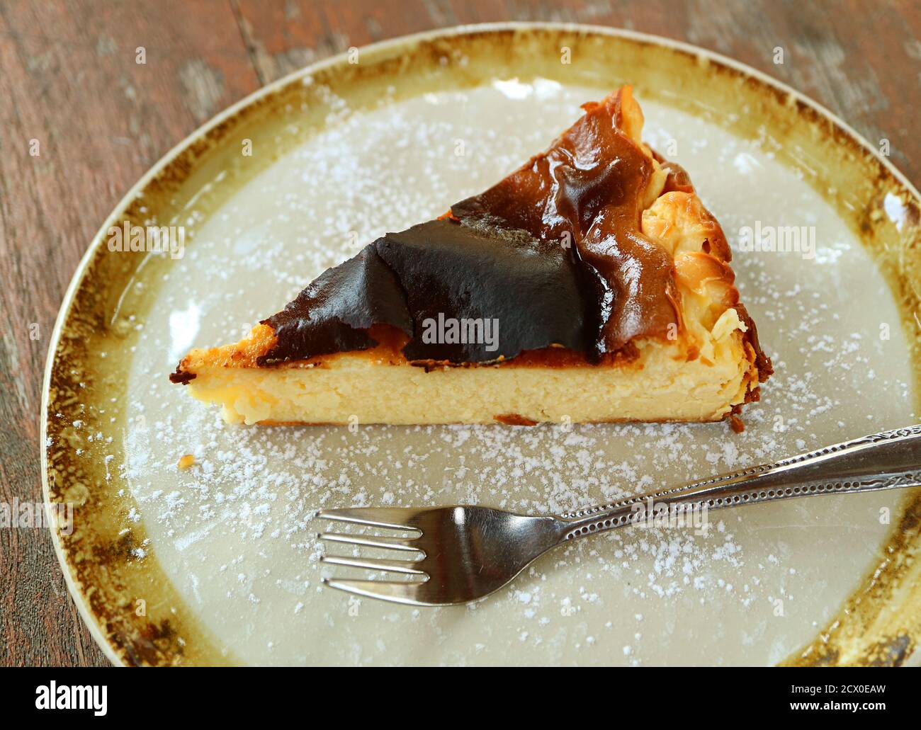 Tranche de cheesecake basque maison brûlé sur une table rustique en bois Banque D'Images