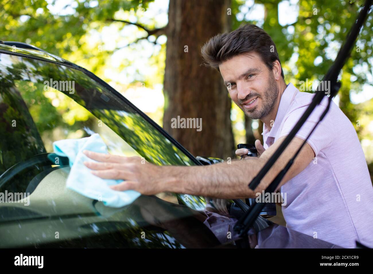 le personnel du service automobile nettoie le pare-brise arrière de la voiture avec un chiffon en microfibre Banque D'Images