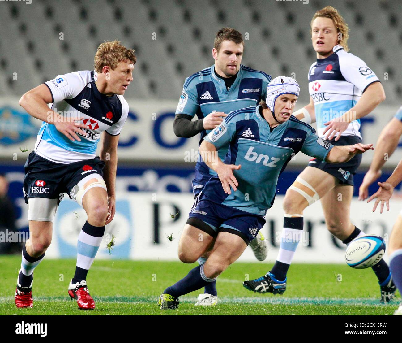 Lachie Munro (in headgear) of New Zealand's Auckland Blues looks to gather  the loose ball, watched by Lachie Turner (L) of Australia's New South Wales  Waratahs, during their Super 15 rugby match