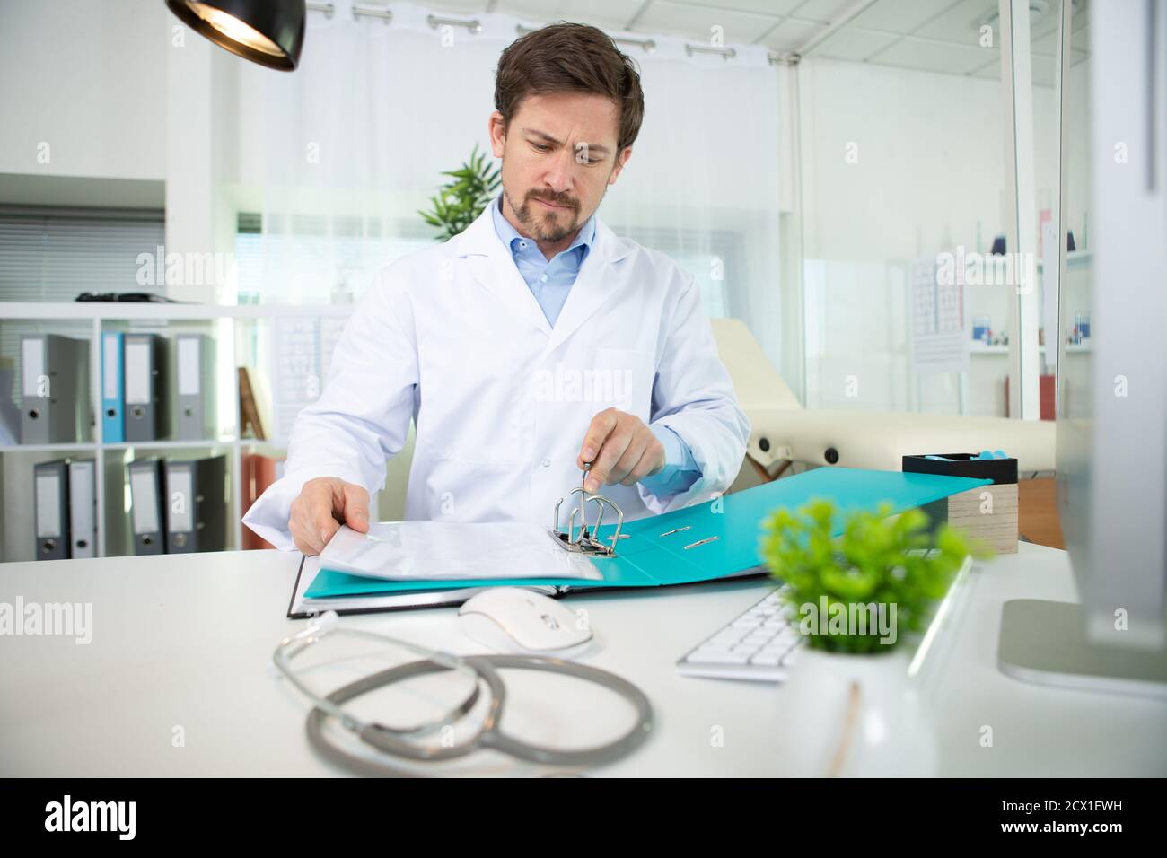 le médecin s'est assis à la réception pour regarder dans le dossier des notes médicales Banque D'Images