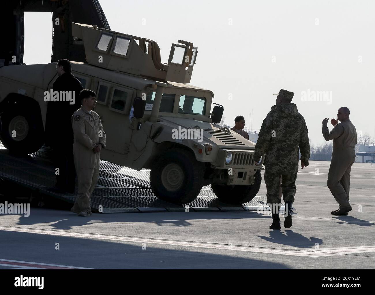 Un militaire ukrainien (2e R) considère comme le premier avion des États-Unis avec une aide non létale, dont dix véhicules Humvee, est déchargé à l'aéroport de Borispol près de Kiev, le 25 mars 2015. Les États-Unis ont envoyé une aide non létale supplémentaire à l'Ukraine, y compris des drones non armés et des véhicules Humvee, a déclaré un responsable de la défense des États-Unis le 11 mars. Le responsable, s'exprimant à condition d'anonymat, a déclaré que certaines parties du paquet américain, y compris 30 Humvees fortifiés avec une armure supplémentaire, pourraient venir en quelques semaines, tandis que d'autres parties pourraient prendre plus de temps. L'aide intervient alors que l'Ukraine lutte contre une rébellion soutenue par la Russie Banque D'Images
