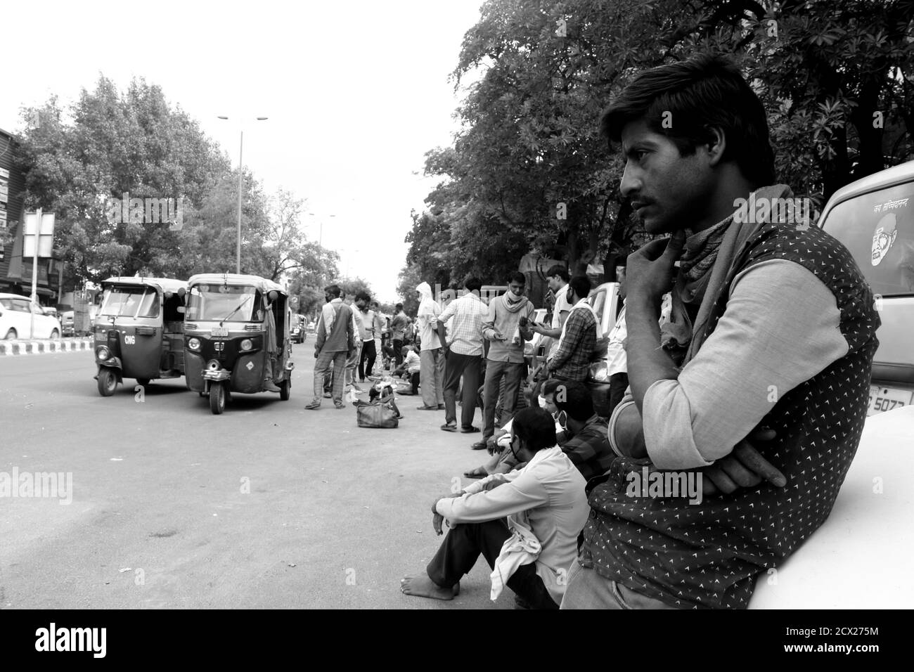 Photo en noir et blanc d'un jeune ouvrier indien de la construction qui attend un travail pour obtenir de la nourriture pour sa famille. Impact de Corona sur les travailleurs et l'industrie. Banque D'Images Photo en noir et blanc d'un jeune ouvrier indien de la construction qui attend un travail pour obtenir de la nourriture pour sa famille. Impact de Corona sur les travailleurs et l'industrie. Banque D'Images