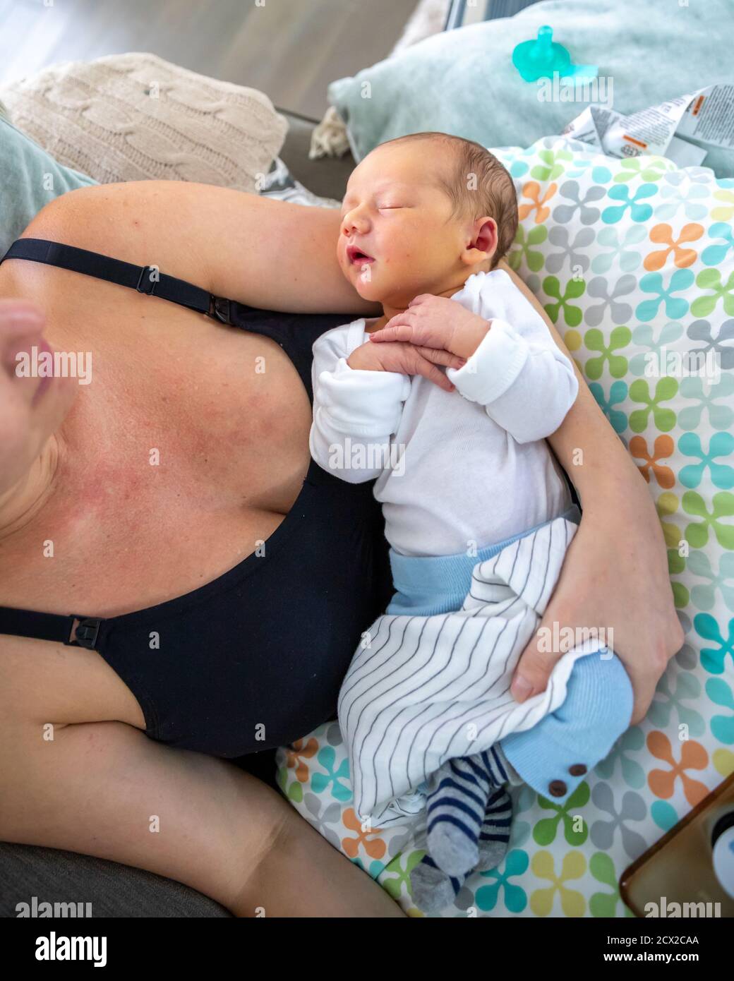 bébé nouveau-né dormant paisiblement dans les bras des mères. Banque D'Images