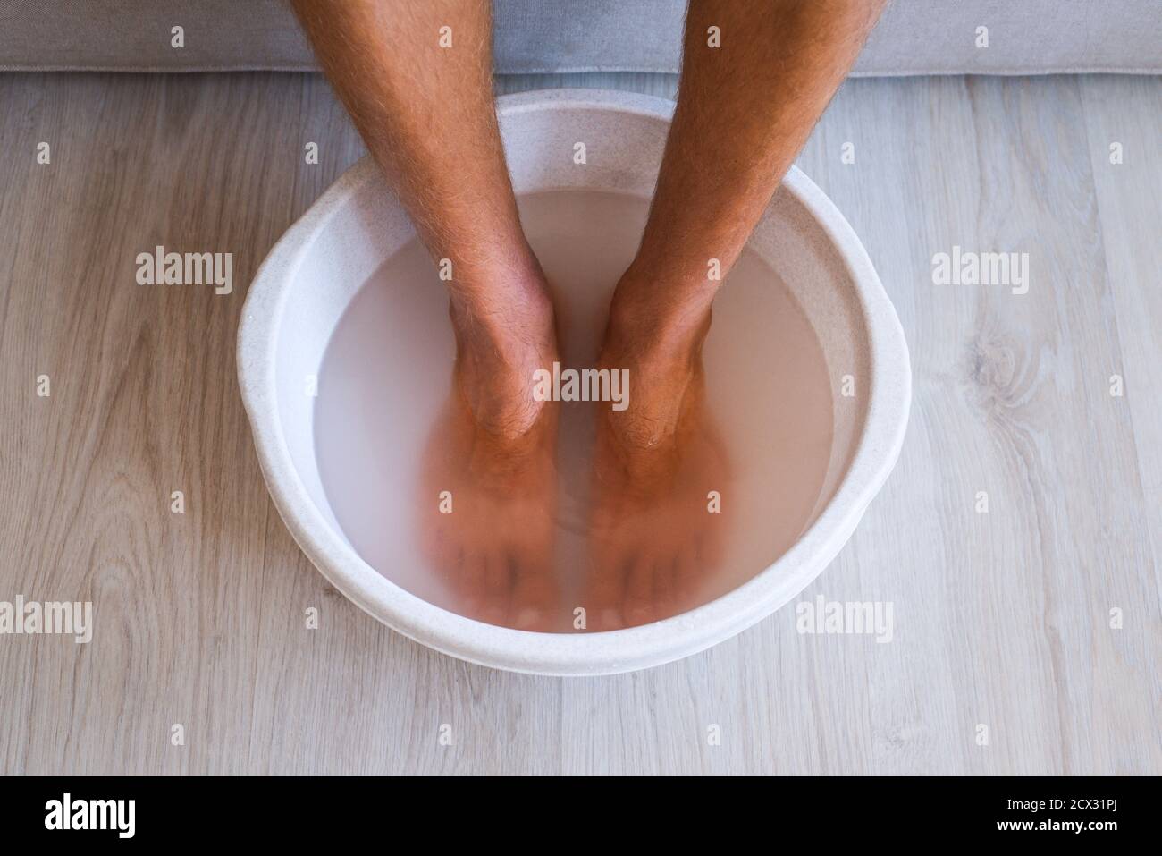 L'homme a fait un bain avec de l'eau chaude et du bicarbonate de soude pour ses pieds. Bain maison pour les pieds secs Banque D'Images
