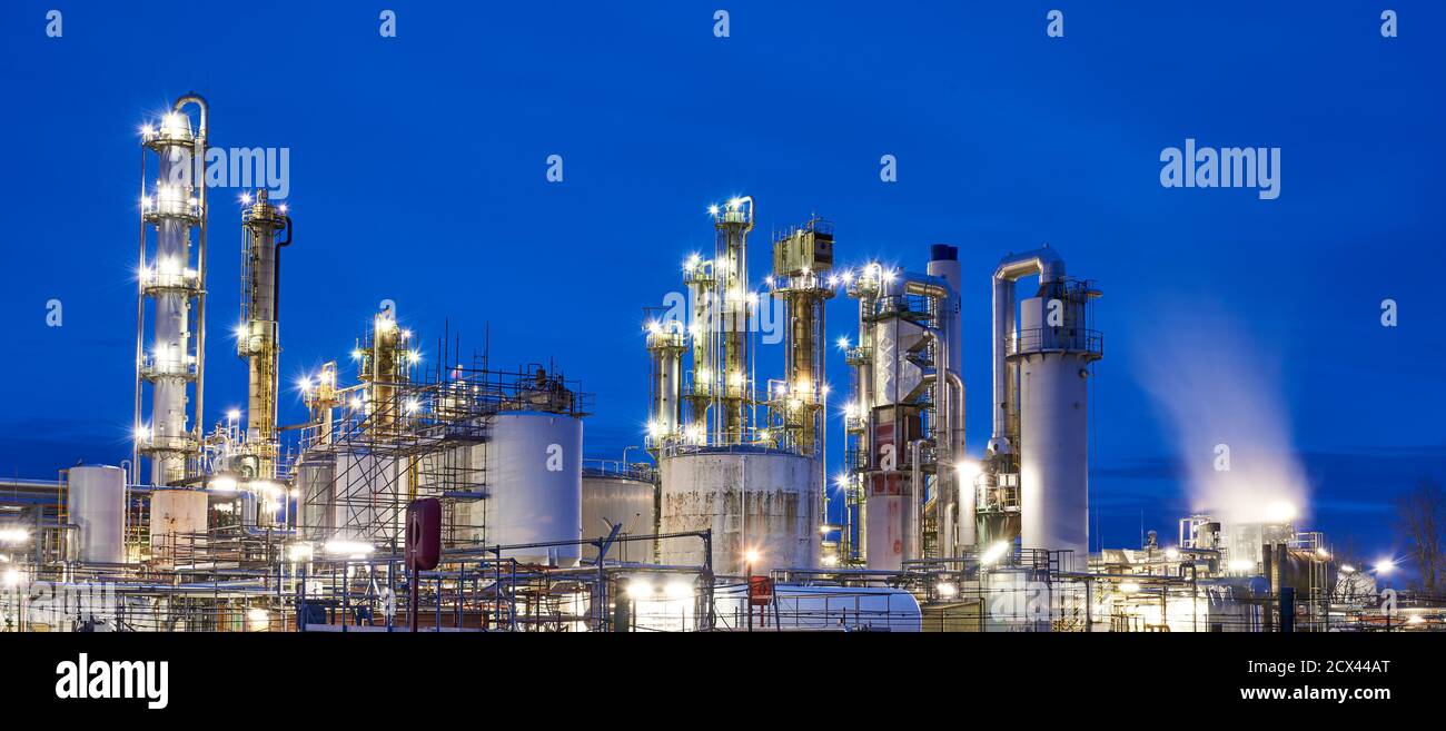 Raffinerie de pétrole après coucher de soleil avec lumières Banque D'Images
