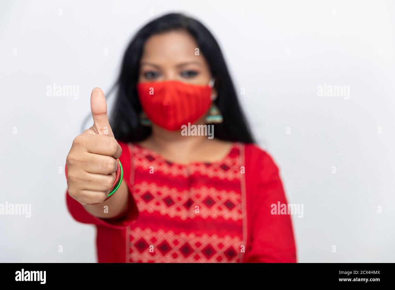 Portrait d'une femme indienne montrant son pouce comme signe de succès et d'approbation, femme debout contre le mur blanc, femme portant la protection Covid 19. Banque D'Images