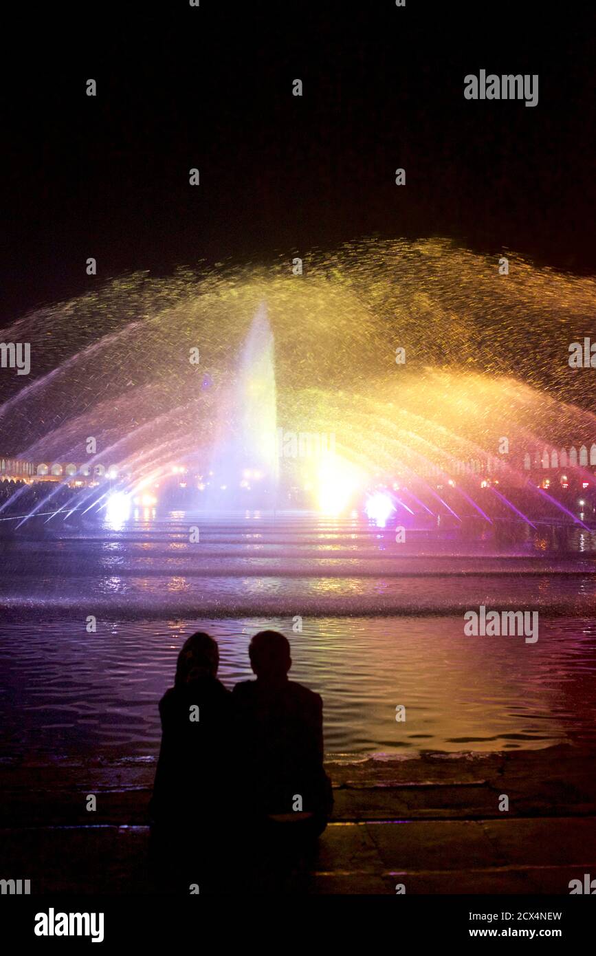 Le couple Trainian s'est taisé la nuit contre les lumières et la fontaine de la place Imam. Ispahan, Iran Banque D'Images