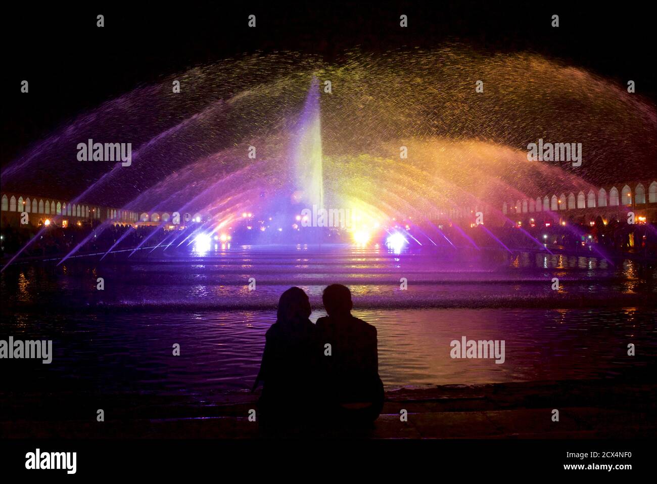 Le couple Trainian s'est taisé la nuit contre les lumières et la fontaine de la place Imam. Ispahan, Iran Banque D'Images
