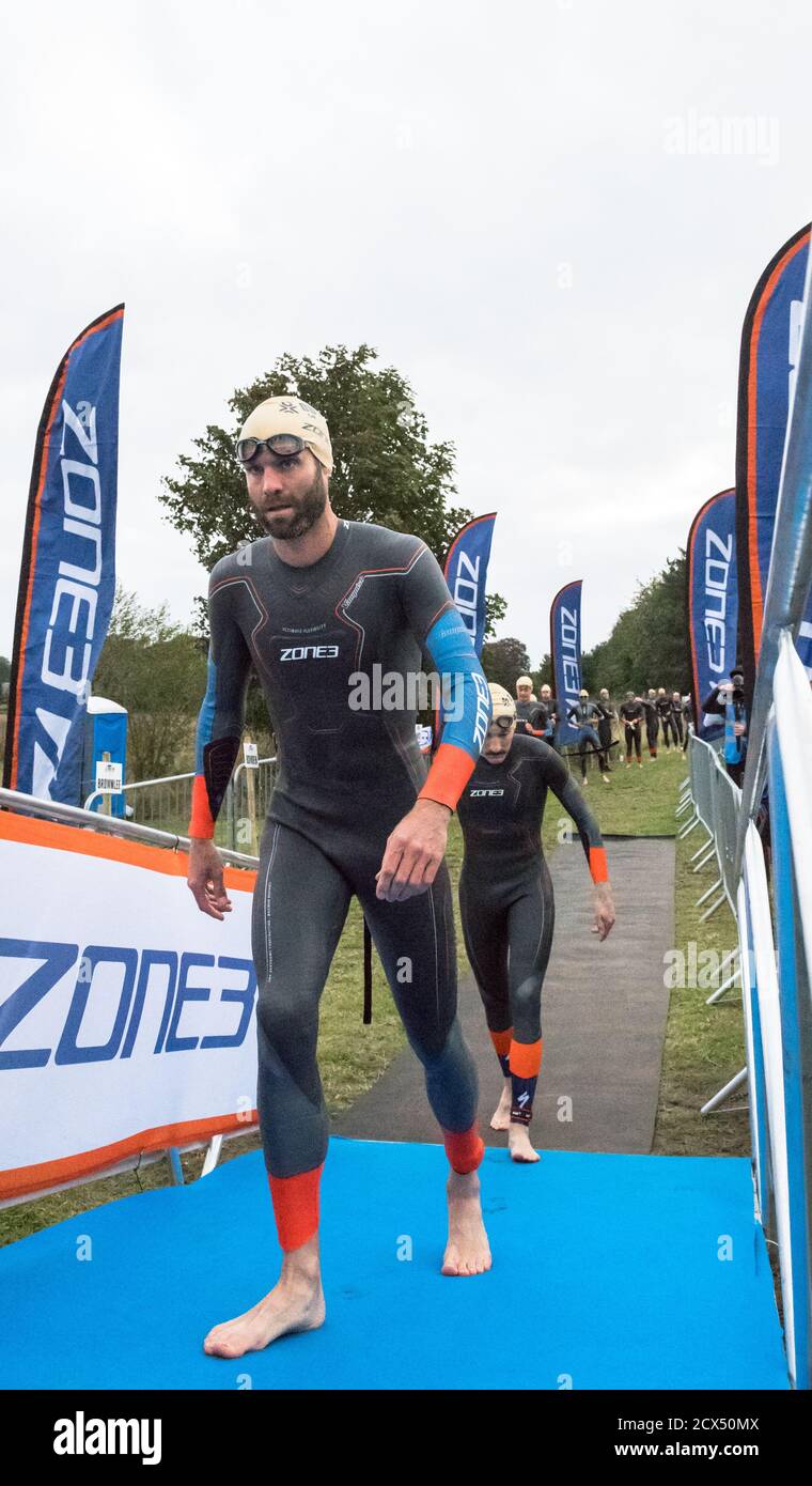 Les athlètes professionnels hommes d'élite se préparant à la première épreuve, la natation, au dernier triathlon de l'année dans leurs combinaisons humides. Banque D'Images