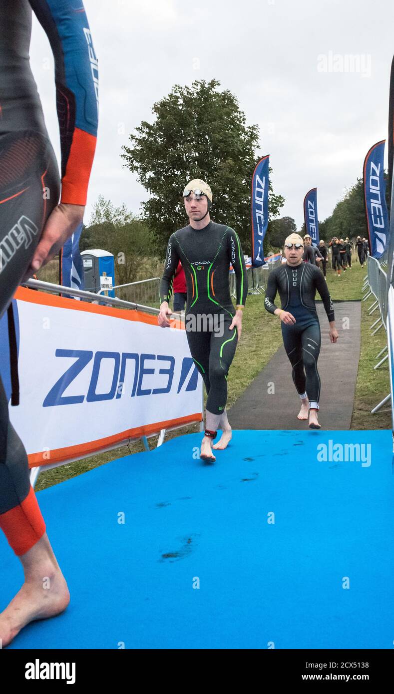 Les athlètes professionnels hommes d'élite se préparant à la première épreuve, la natation, au dernier triathlon de l'année dans leurs combinaisons humides. Banque D'Images