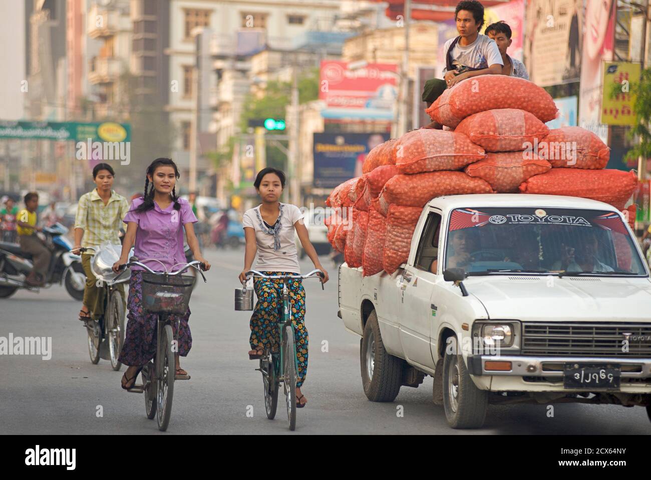 Scène urbaine birmane - véhicule chargé et cyclistes, Mandalay, Birmanie. Myanmar Banque D'Images