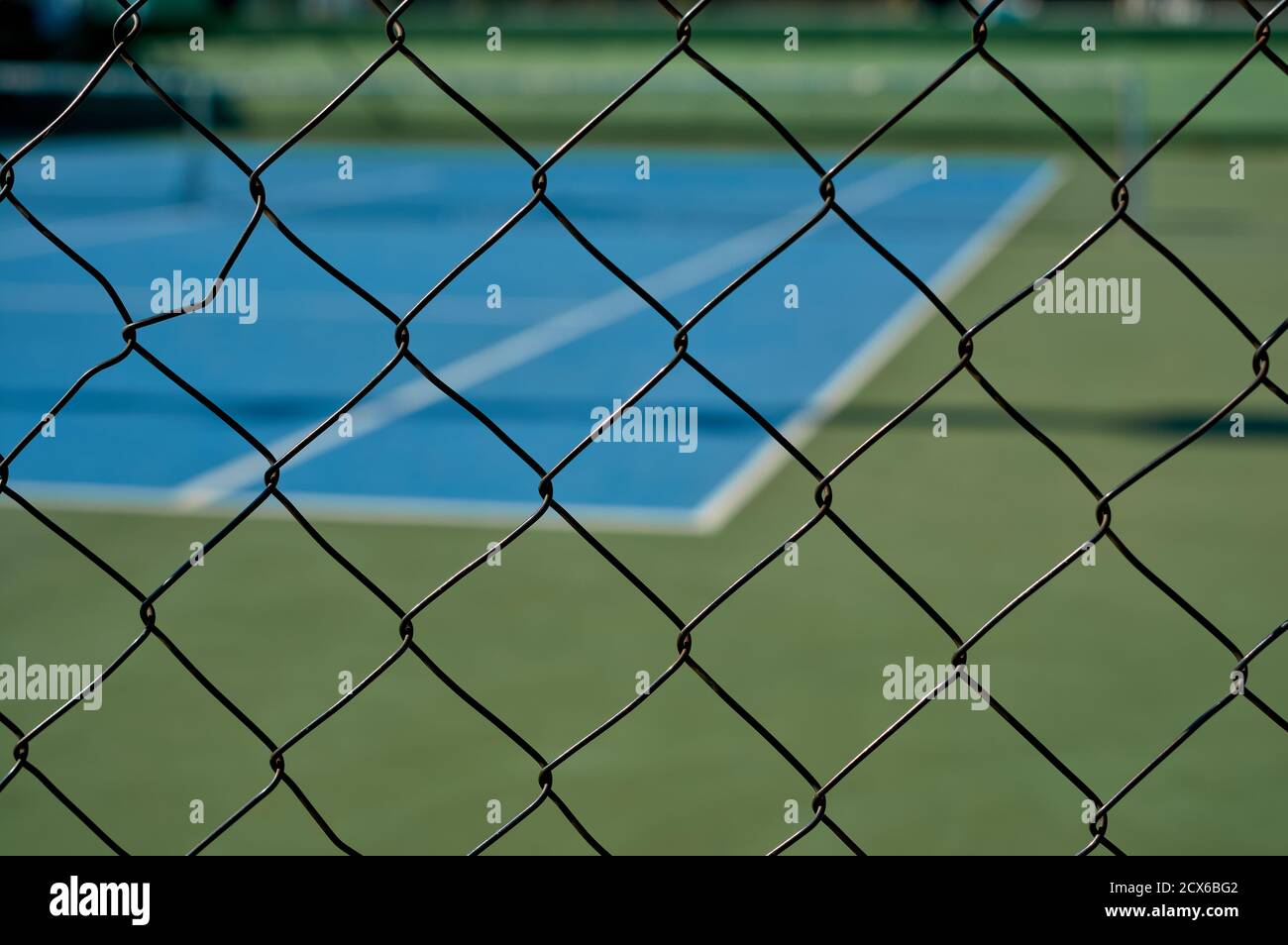 détail d'une vue sur un court de tennis synthétique bleu par une clôture Banque D'Images