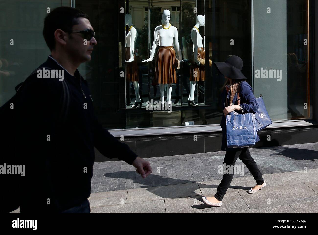 Une femme portant un sac Zara passe devant un magasin Zara dans le centre  de Madrid le 18 mars 2014. Inditex, le plus grand détaillant de mode au  monde, va accélérer les