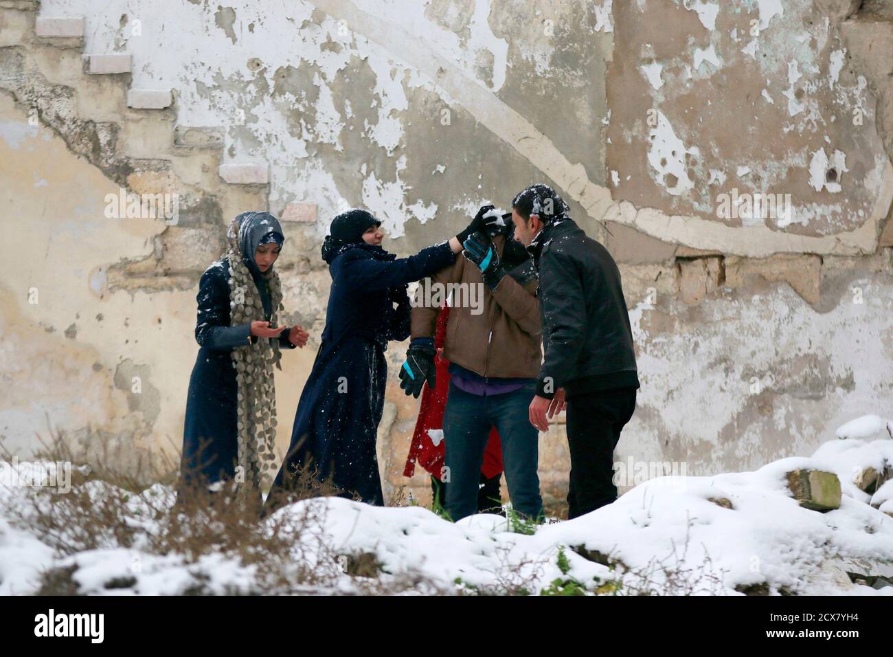 Residents play with snow in Aleppo January 11, 2015. A storm buffeted the  Middle East with blizzards, rain and strong winds, keeping people at home  across much of the region and raising