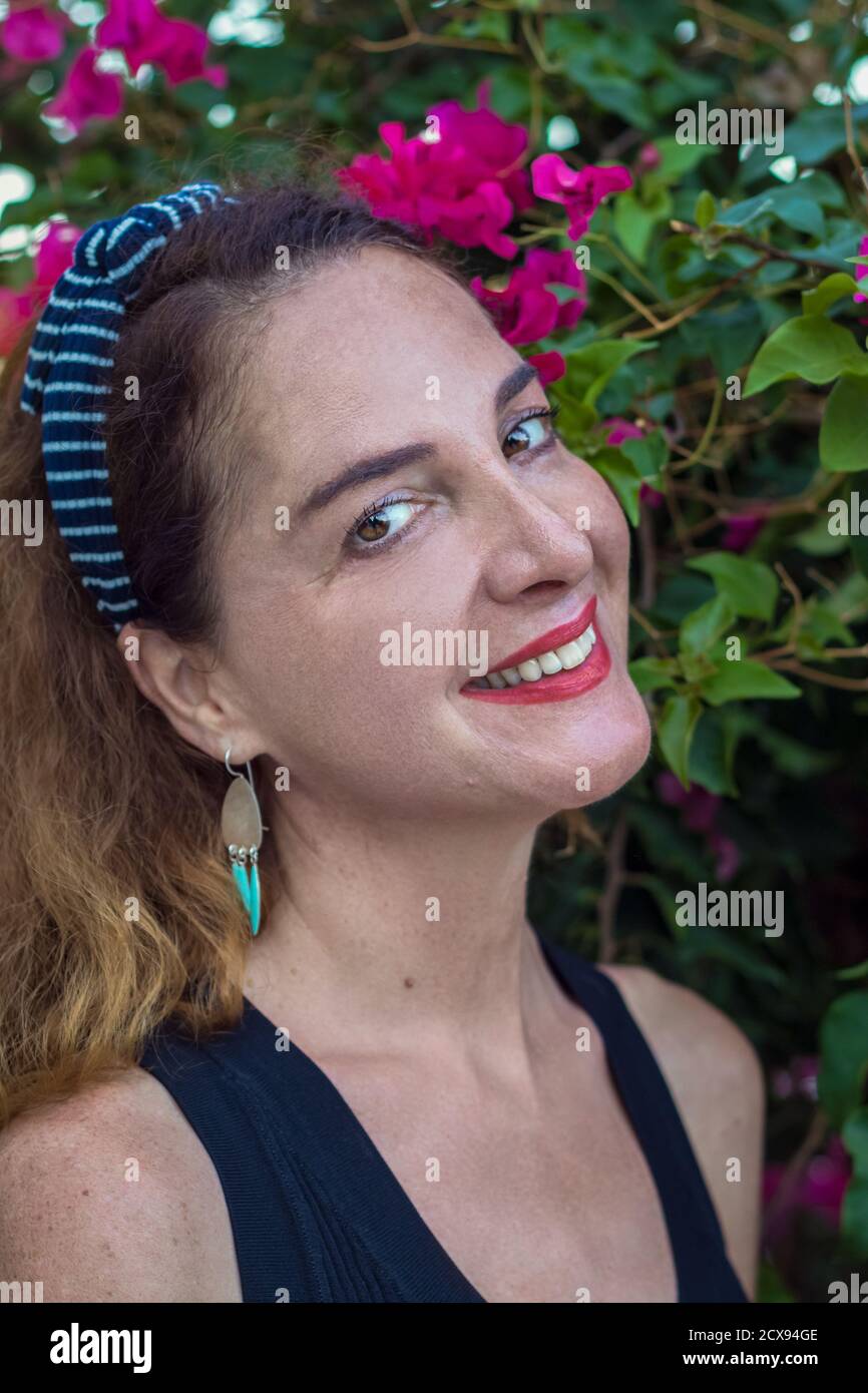 Portrait d'une femme 40-45 ans regardant l'appareil photo portant un bandeau, souriant, heureux, à l'extérieur. Banque D'Images