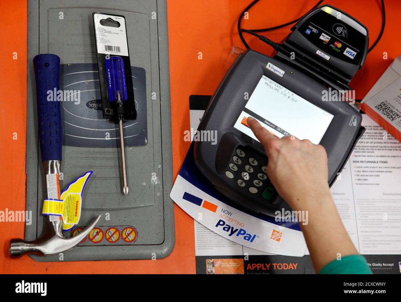 A public relations representative demonstrates how a PayPal customer can  pay for goods using their mobile phone number at a cashier station at a  Home Depot store in Daly City, California, February
