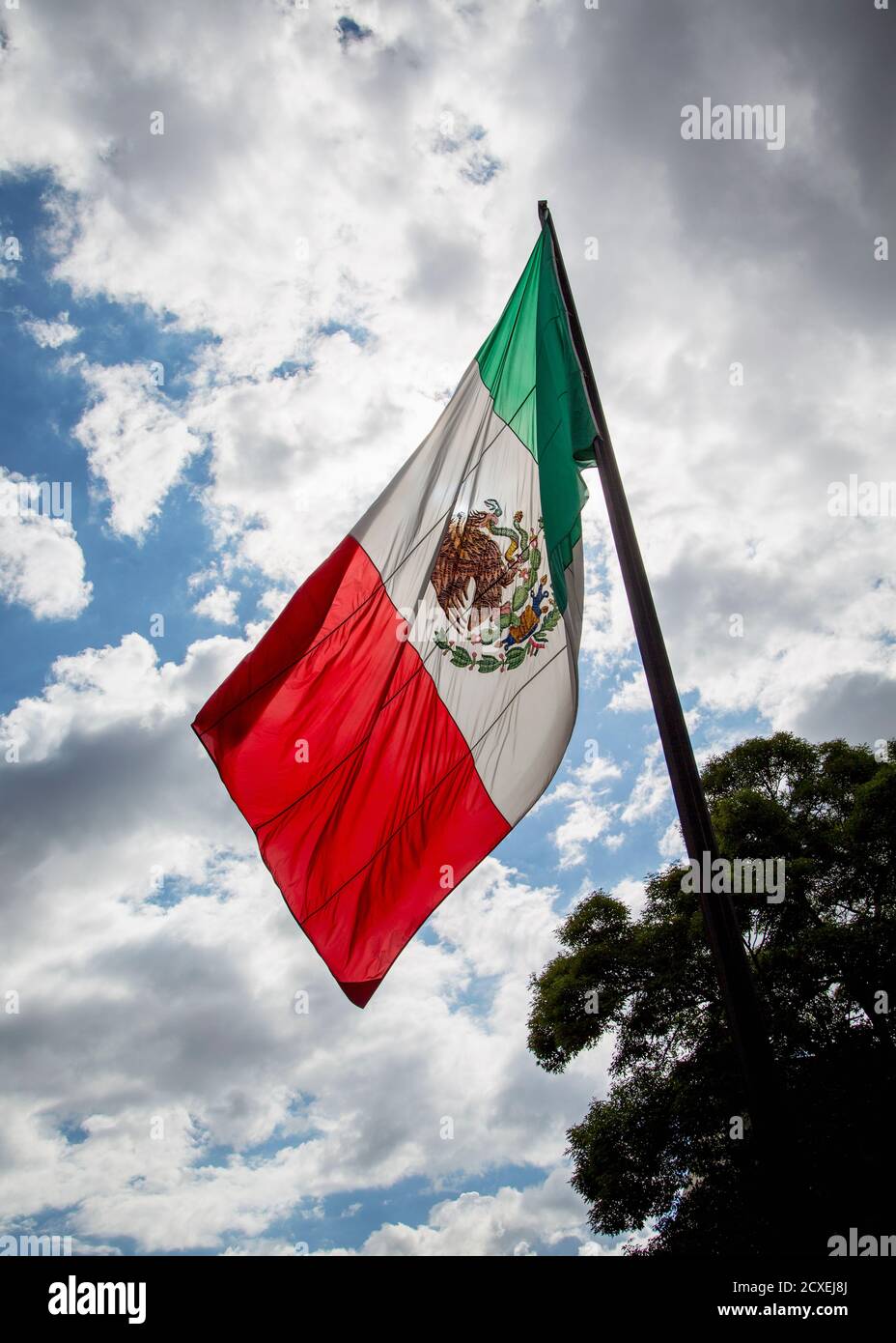 Le drapeau mexicain vole en face d'une tempête de nuages Ciel Banque D'Images