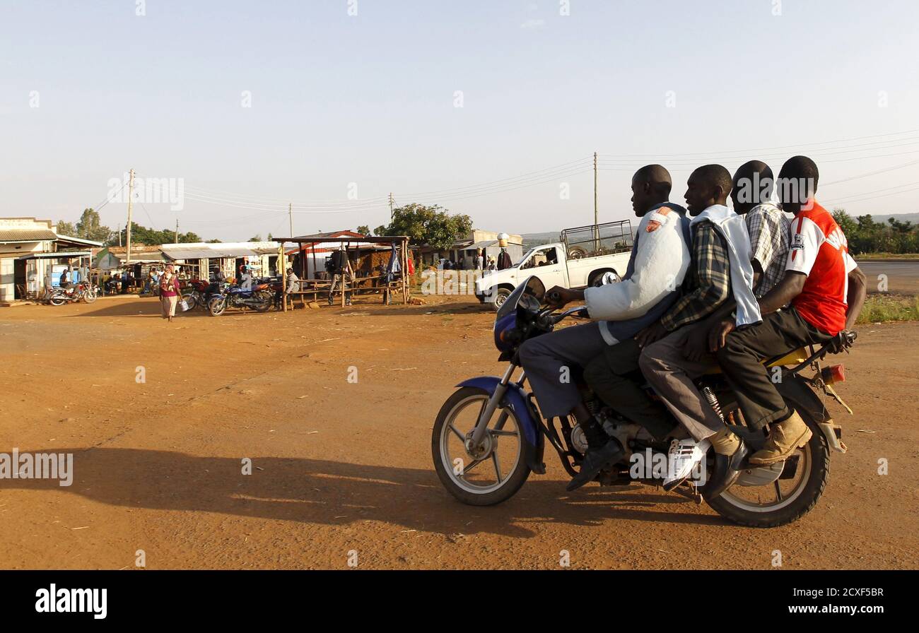 Un taxi à moto transporte trois passagers après le centre d'échange du village de Kogelo, à l'ouest de la capitale du Kenya Nairobi, le 15 juillet 2015. Le président américain Barack Obama se rend au Kenya et en Éthiopie plus tard ce mois-ci. Sa maison ancestrale de Kogelo est la maison de Sarah Hussein Obama, sa belle-grand-mère. Le village kenyan, lieu de sépulture du père d'Obama, comprend une mine d'or à ciel ouvert, une boucherie de porc, une école nommée d'après leur fils le plus célèbre et des étals de marché en plein air. Les villageois se déplacer en taxi à moto ou à pied pendant qu'une voiturette transporte l'eau. Des enfants, certains d'entre eux ont nommé Obama en honneur o Banque D'Images