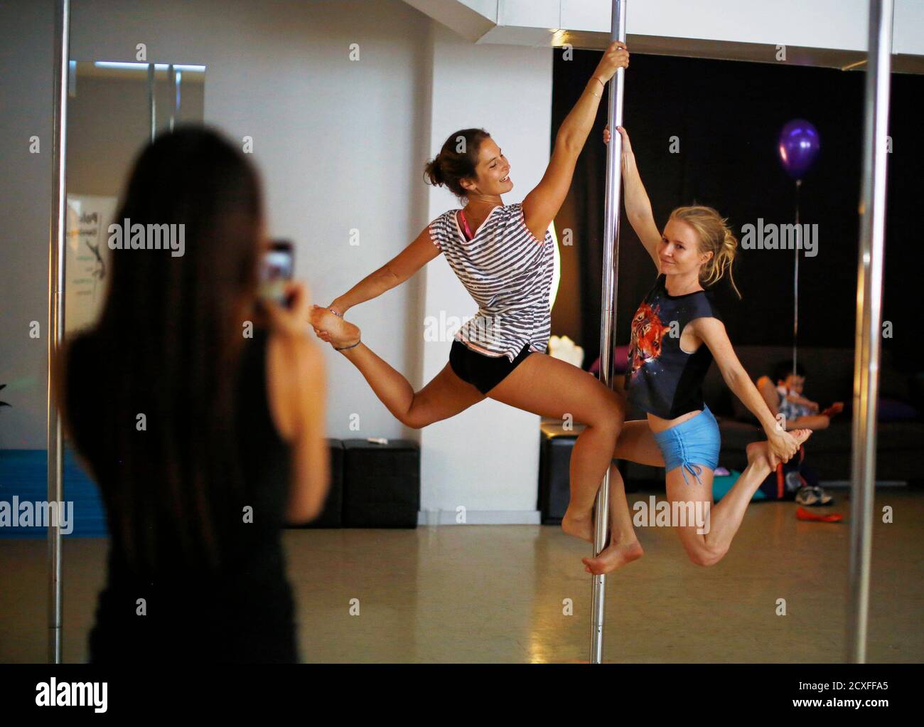 Women practise a pole dancing move during an International Women's Day  event at a women's-only pole dancing fitness studio called Studio  Exclusive, in Sydney March 8, 2014. The event raised money for "