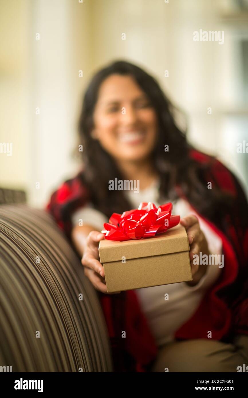 Heureux femme enveloppée dans une couverture chaude tenant un cadeau. Banque D'Images