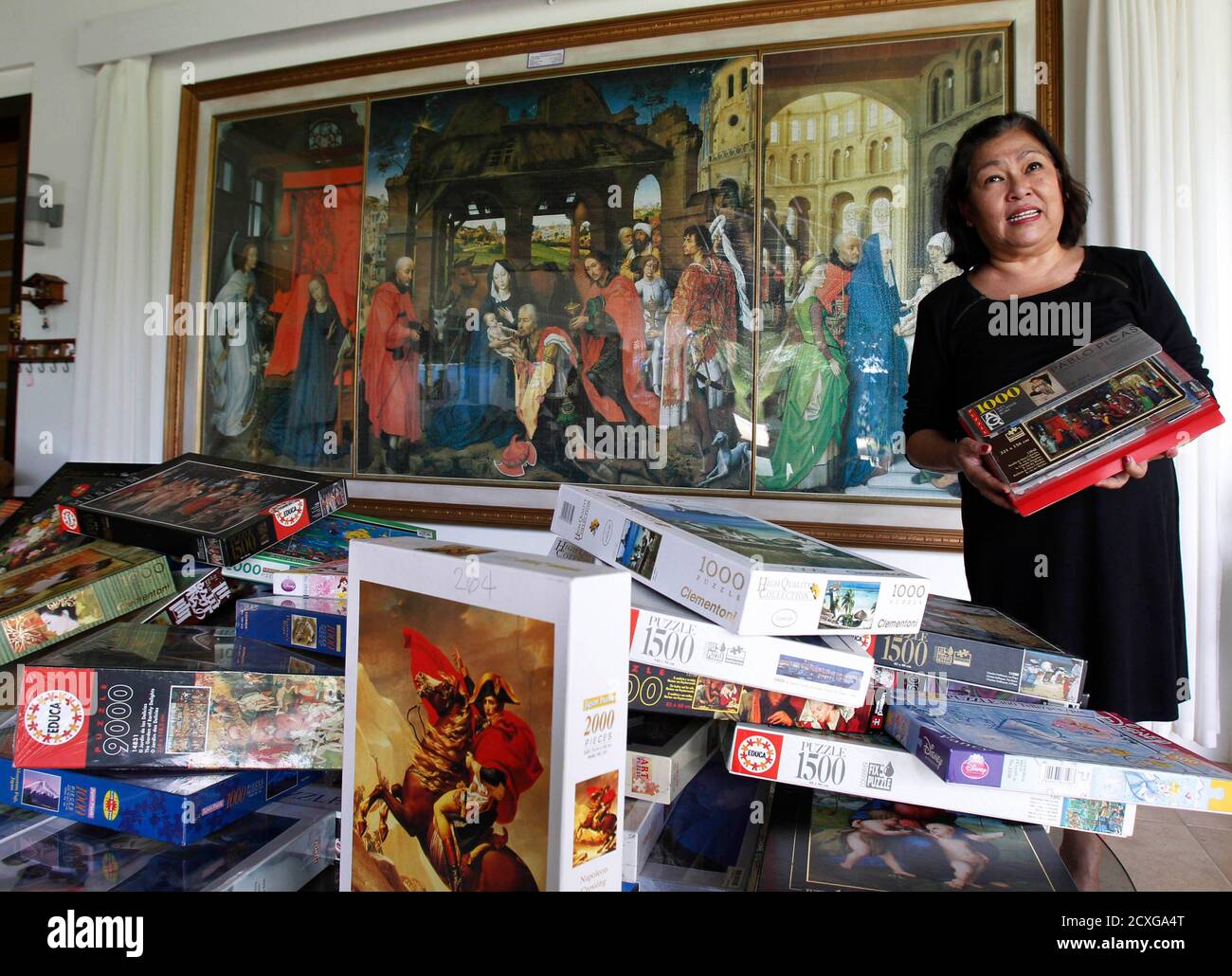 Filipino businesswoman Gina Lacuna shows her collection of jigsaw puzzle  boxes as she stands in front of an 18,000-piece jigsaw puzzle of Retablo De  Santa Columba, which took her 1095 hours to