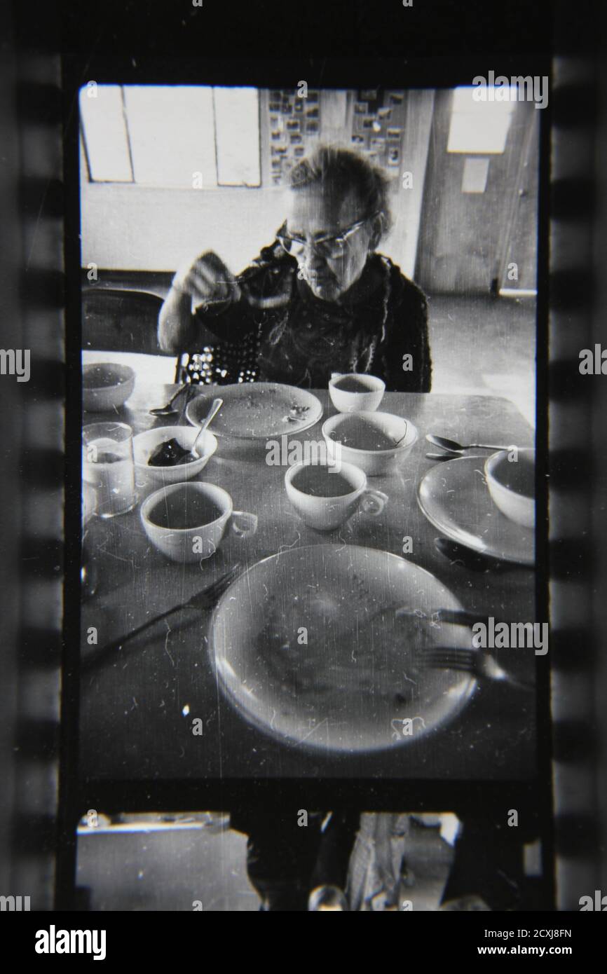 Belle photographie en noir et blanc vintage des années 1970 des enfants qui apprécient le déjeuner à la cafétéria. Banque D'Images