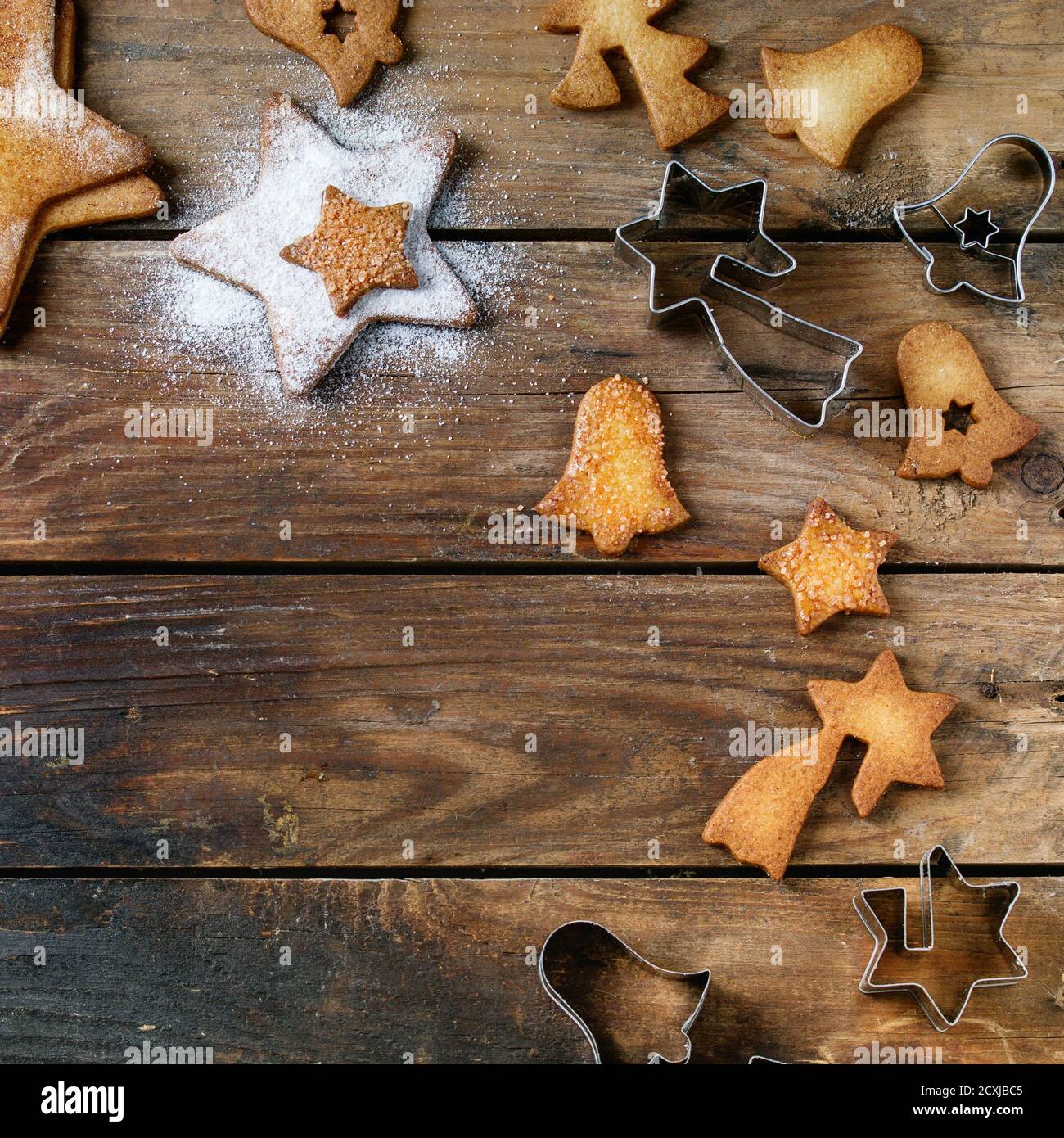 Biscuits de Noël faits maison sablés en forme d'étoile de sucre de taille différente avec sucre en poudre et emporte-pièces sur la vieille surface en bois. Bac gâteries de Noël Banque D'Images