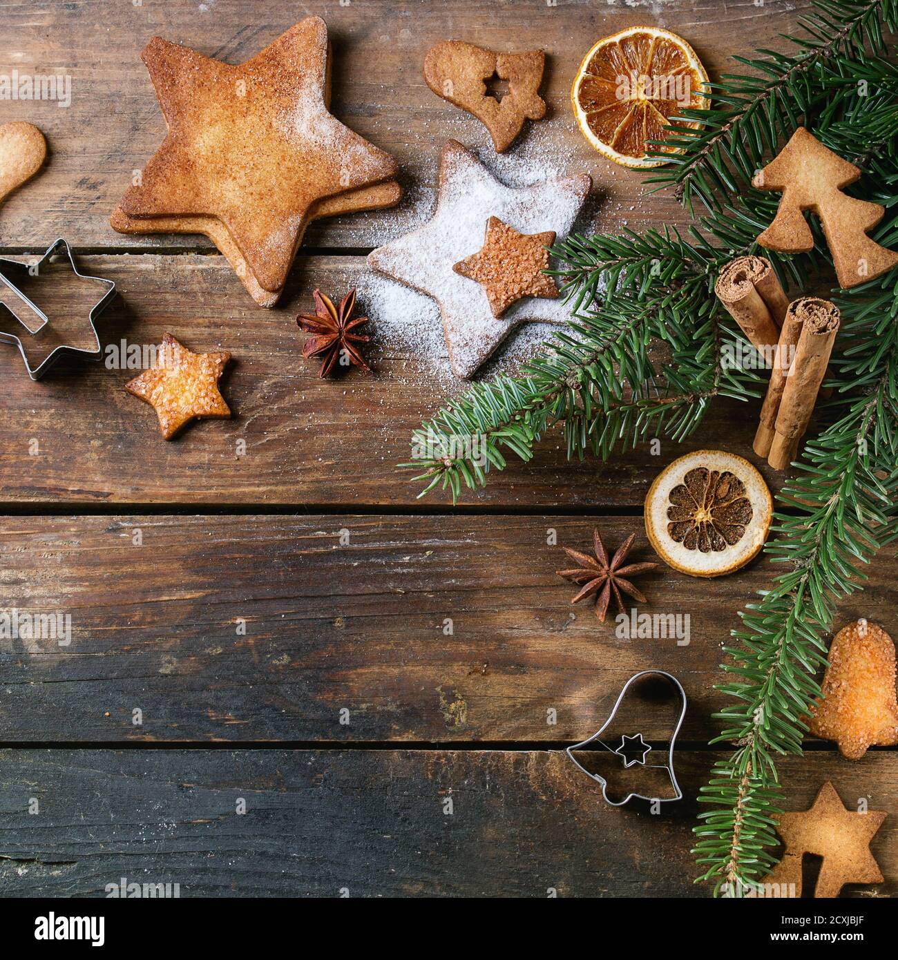 Biscuits de Noël faits maison en forme d'étoile de sucre de taille différente avec sucre en poudre, cannelle, sapin vert et emporte-pièces sur surface en bois Banque D'Images