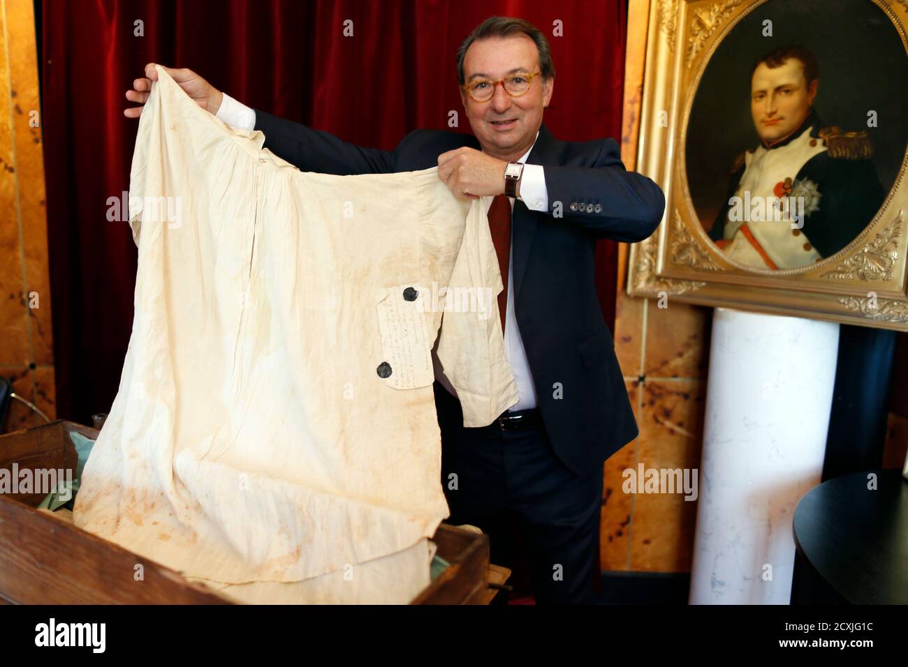 Auctioneer Jean-Pierre Osenat holds the French Emperor Napoleon Bonaparte's  shirt, marked with his initial, a captital N with a crown, and the stains  of sweat from his illness, at auction house Osenat