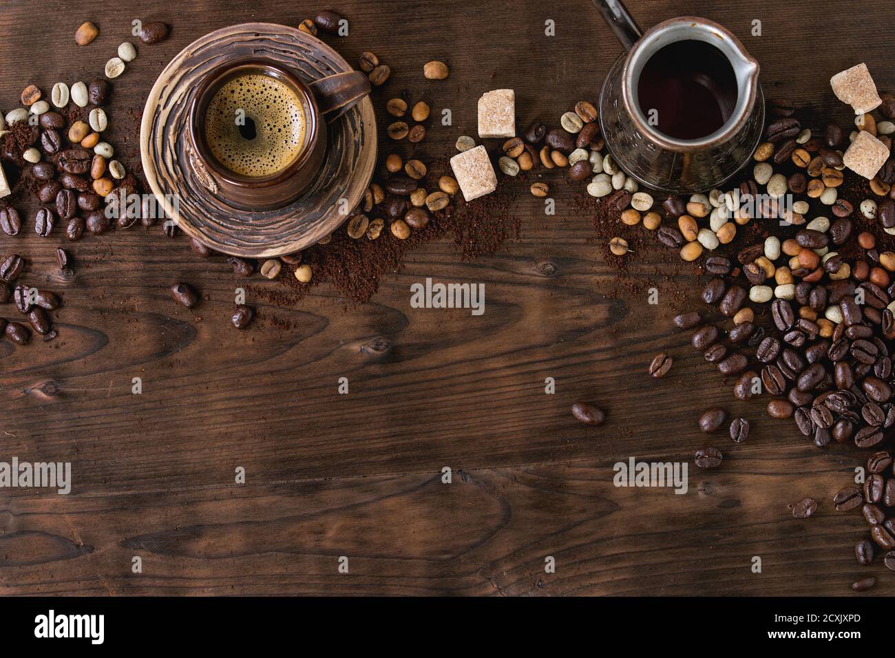 Arrière-plan sur le thème du café avec différents grains de café vert et noir, sucre, pot et tasse de café sur fond de bois sombre. Café boisson co Banque D'Images
