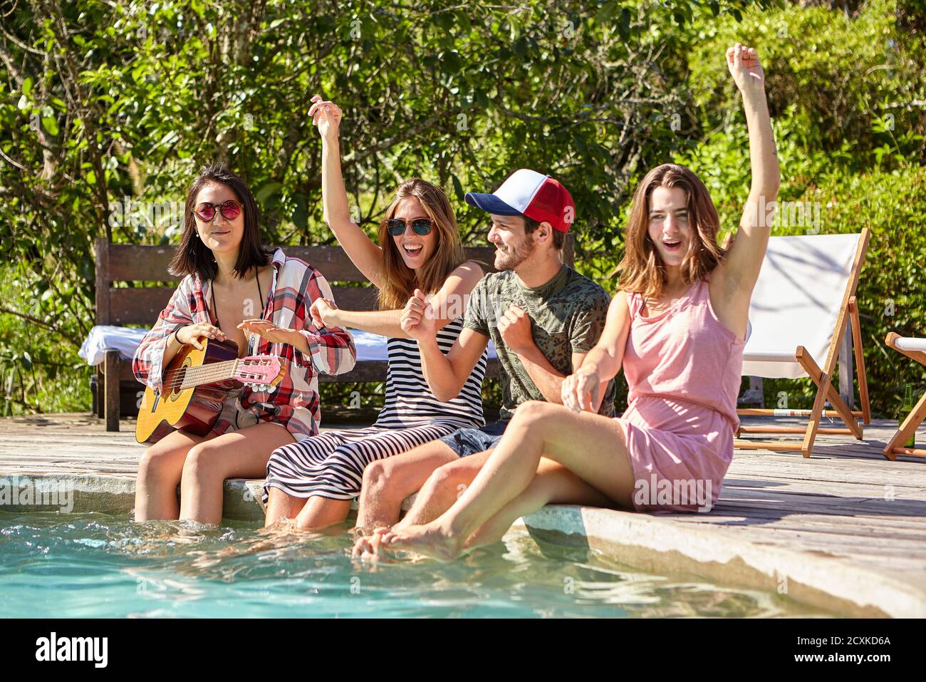 Jeunes amis qui apprécient la fête au bord de la piscine Banque D'Images