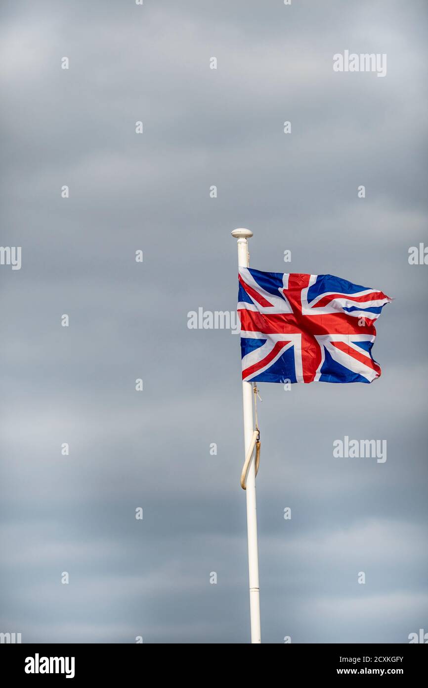 Drapeau Union Jack volant dans un vent fort sur fond nuageux Banque D'Images