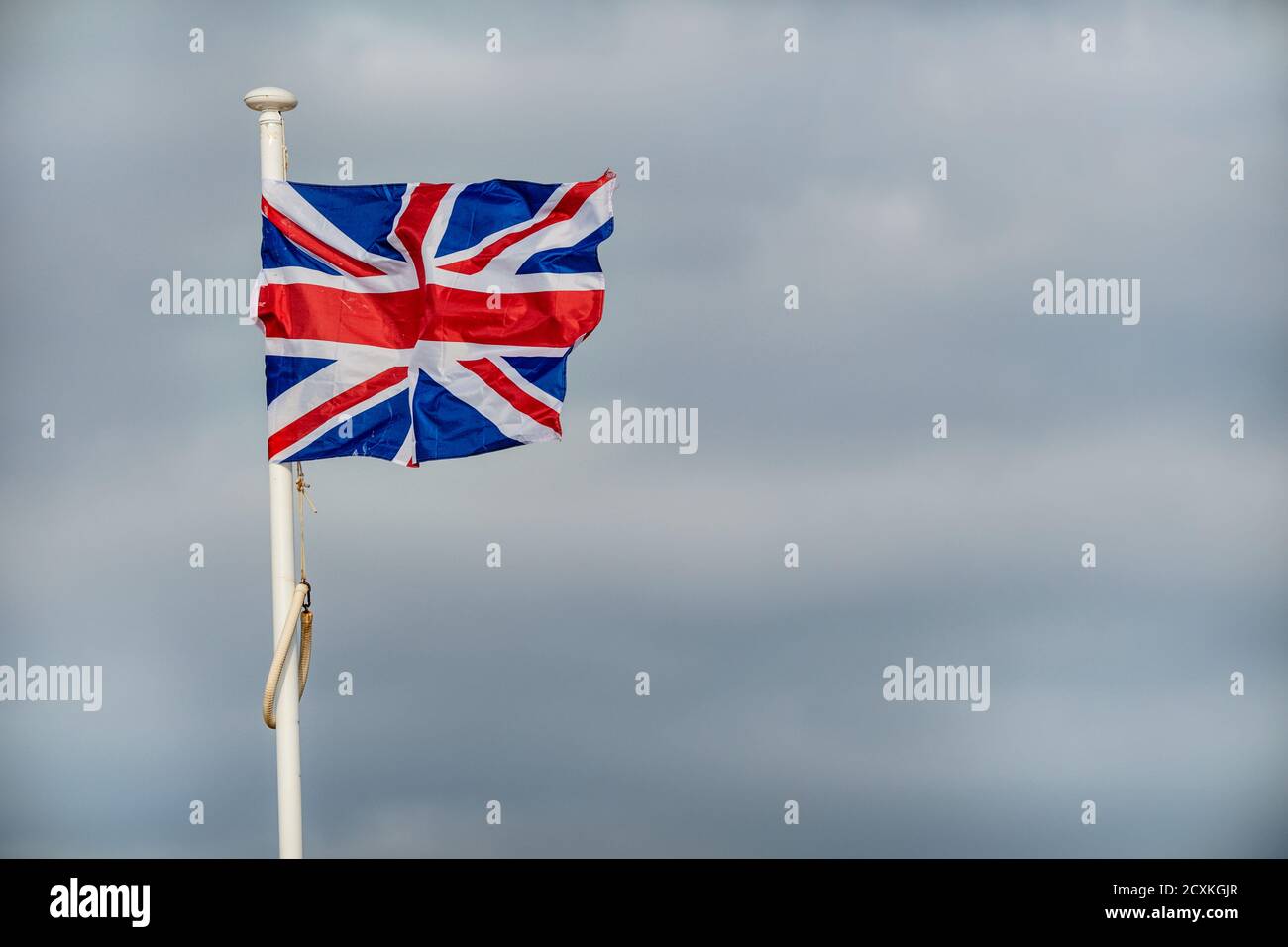 Drapeau britannique flottant dans un vent fort sur fond nuageux Banque D'Images