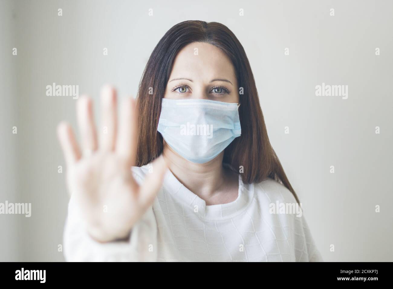 Gros plan d'une jeune femme portant un masque sanitaire montrant un panneau « top » avec sa main Banque D'Images