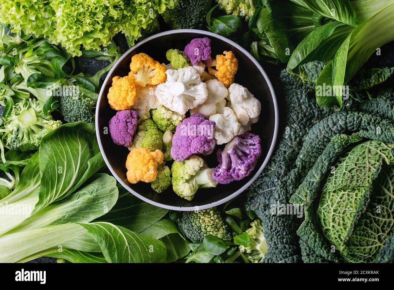 Variété de légumes verts crus des salades, la laitue, le bok choy, maïs, brocoli, chou-fleur jeunes colorés ronds en noir bol. Food backgrou Banque D'Images
