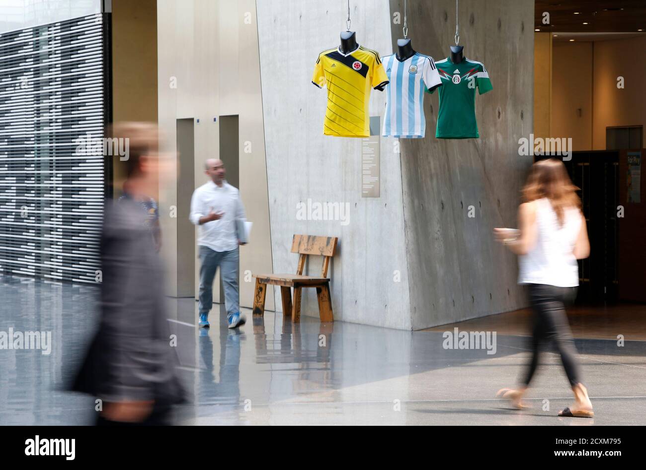 People walk through the headquarters of Adidas before the company's news  conference in the northern Bavarian town of Herzogenaurach, near Nuremberg  June 24, 2014. German sportswear firm Adidas expects to meet its