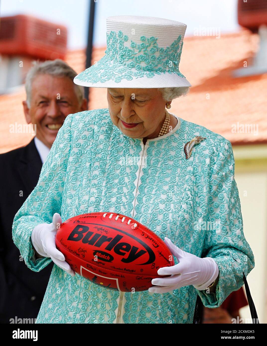 Britain's Queen Elizabeth holds an Australian rules football during her  visit to Clontarf Aboriginal College in Perth October 27, 2011. Queen  Elizabeth is in Australia for an eleven-day official visit. REUTERS/Daniel  Munoz (