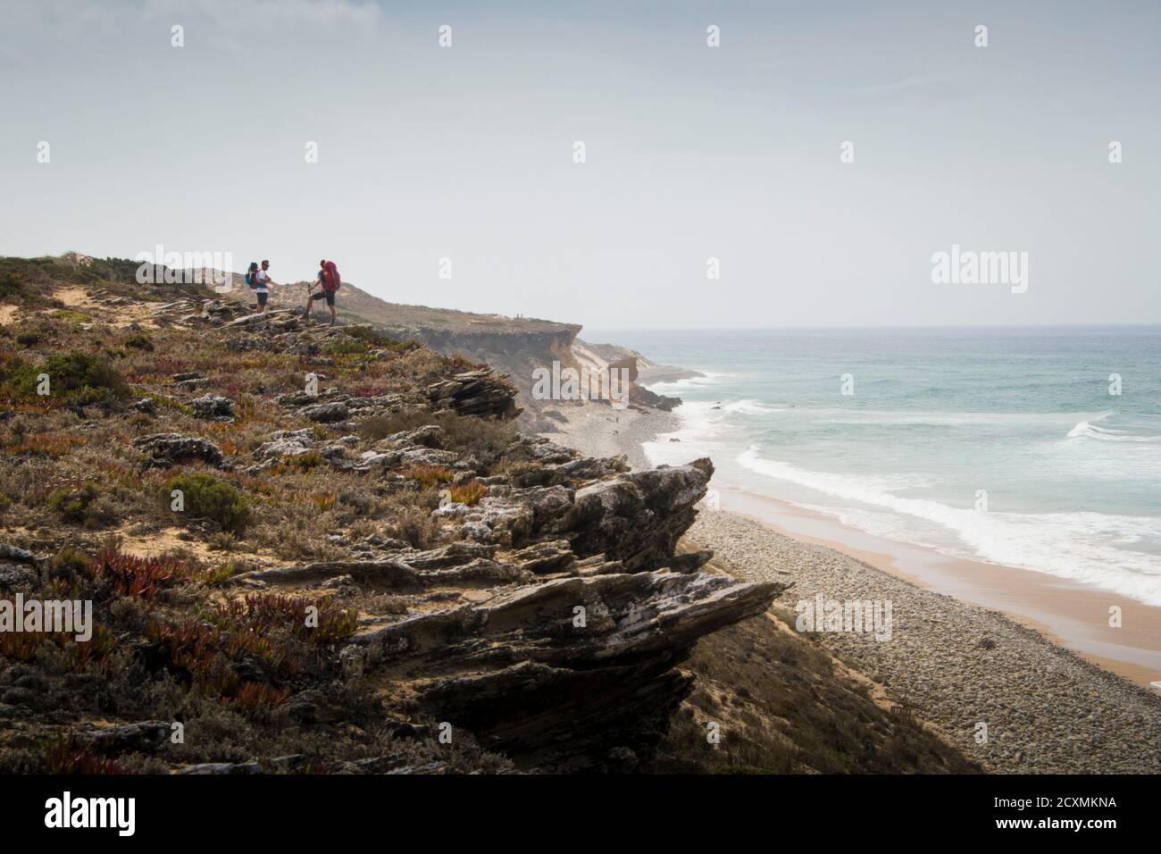 Deux randonneurs marchent le sentier le long des dunes, se tenant sur une falaise à côté d'un paysage de plage par une journée grise Banque D'Images