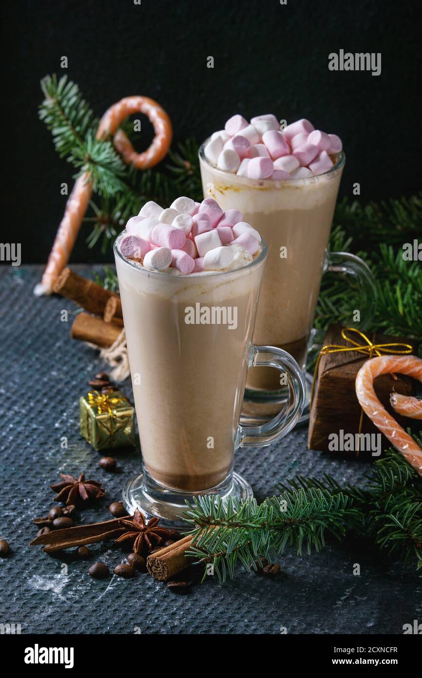 Deux verres de café latte avec guimauve rose avec décoration de Noël, bonbons, épices, les grains de café et de sapin sur fond texture sombre. Haut de la vie Banque D'Images