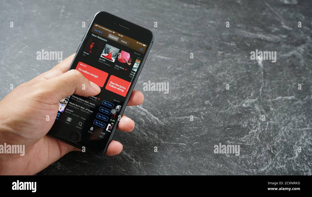 Mataram, Indonésie - 1 octobre 2020 : main tenant Apple iPhone 8 avec Apple itunes Music App sur l'écran sur pierre, vue du dessus. Banque D'Images
