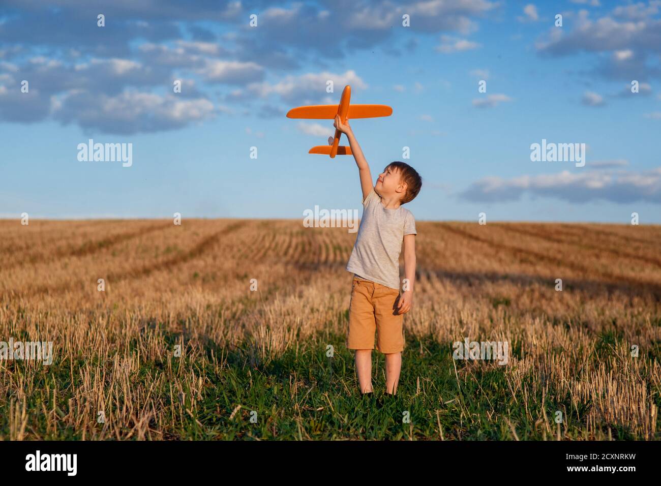 Enfant heureux courant avec avion jouet sur fond de ciel concept de famille heureux. Rêve d'enfance Banque D'Images