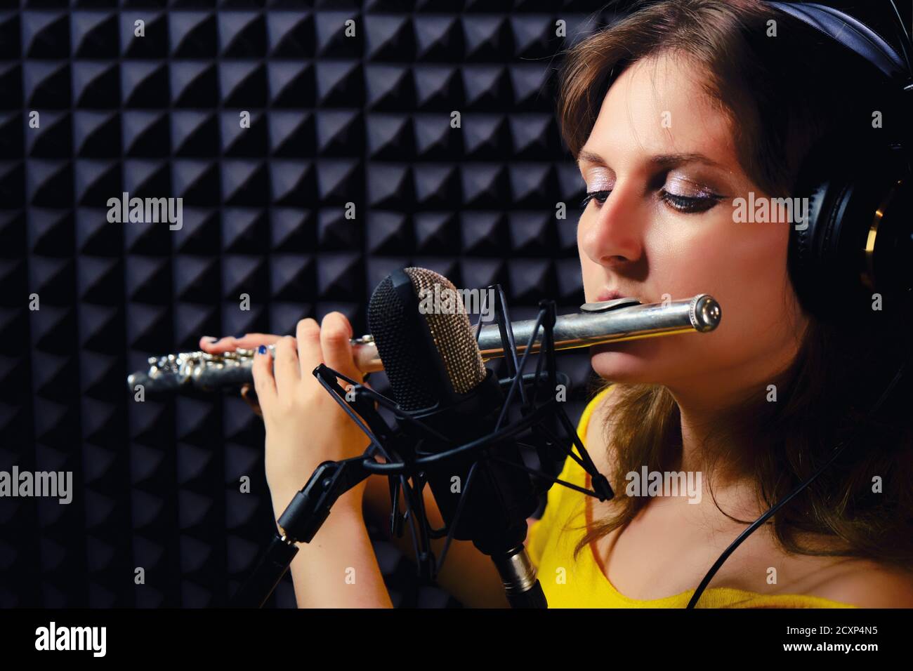 Le flûte joue dans un studio de musique, un espace de copie. Enregistrez des instruments de musique à vent avec un microphone professionnel. Femme dans le casque flûtiste Playi Banque D'Images