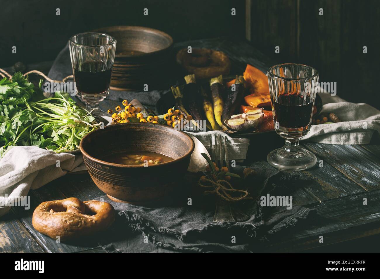 Maison de vacances d'automne avec décoration de table bols de soupe de pommes de terre carottes chaud, la citrouille, la carotte, l'ail, coriandre fraîche, bretzels, pain, vin rouge Banque D'Images