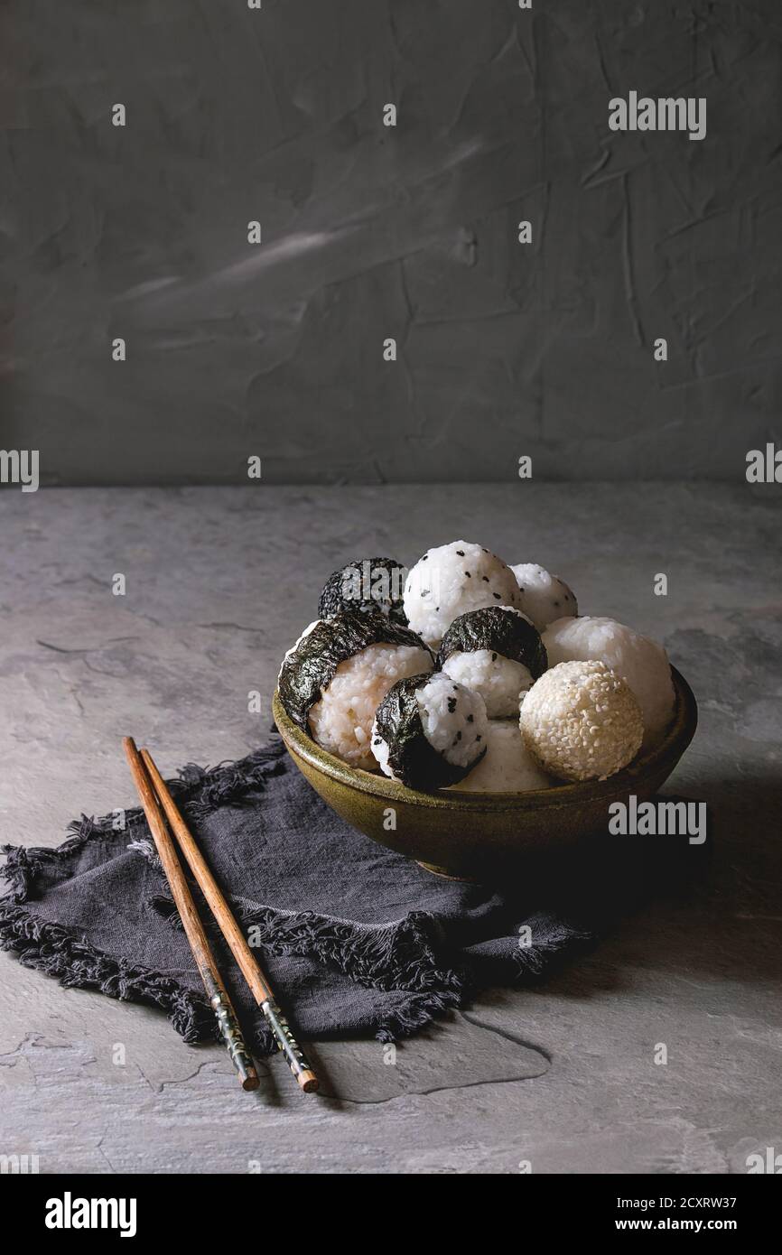 Bol avec différentes tailles de boules de riz et sésame noir avec des Algues Nori, servi avec des œufs durs, de la sauce de soja, des baguettes sur le tableau gris. Asian sty Banque D'Images